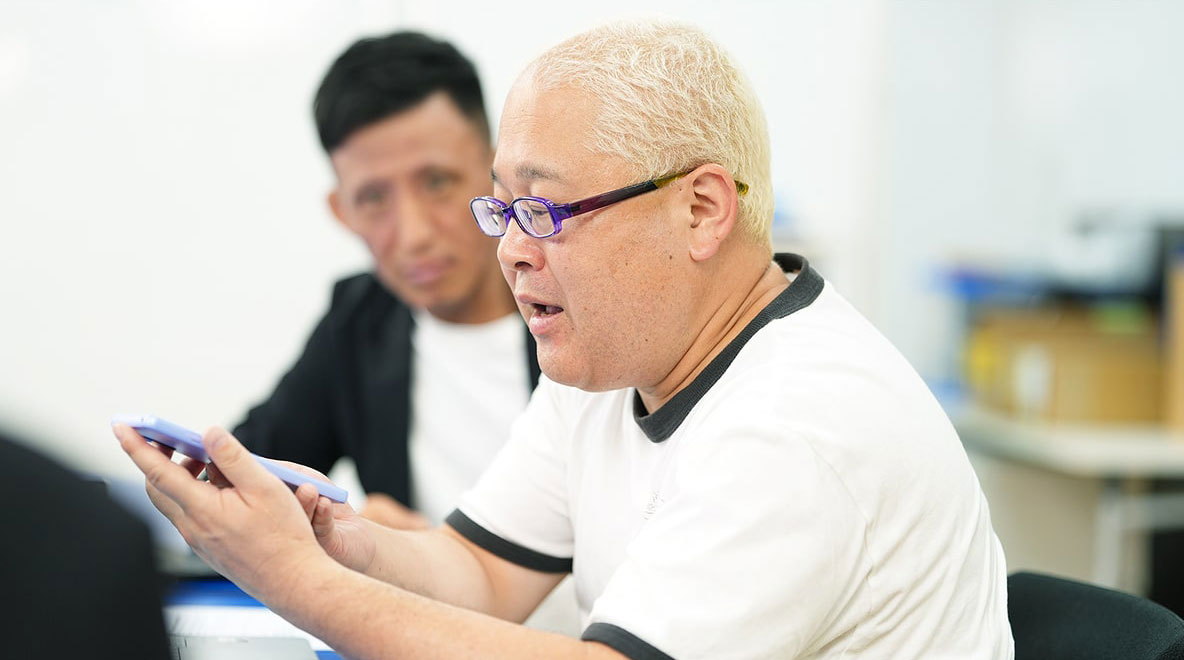 スマートフォンで発話支援アプリを使う鈴木さんの写真