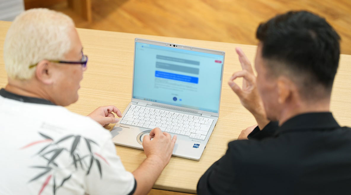 ノートパソコンで発話支援アプリを使う鈴木さんと中田さんの写真